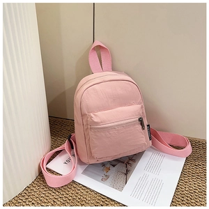 Detail of pink nylon mini backpack with zip pocket and brand label on woven mat
