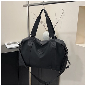 Detail of black nylon travel bag featuring reinforced handles and adjustable strap