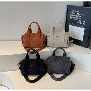 Detail view of nylon Boston bags in caramel, beige and grey on a clean display