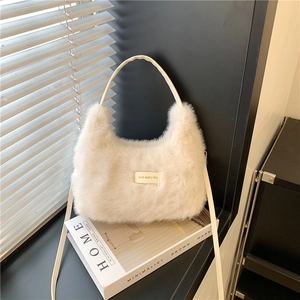 Minimalist cream plush shoulder bag with LOVE EVERY DAY tag on a decorative book