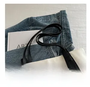Détail du sac seau en toile avec bandoulière en cuir noir et finitions de coutures ovales