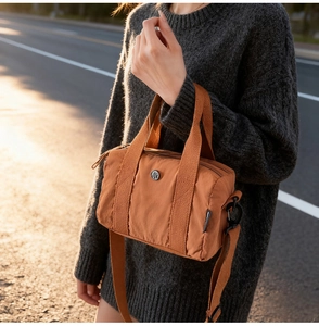 Detailed view of the orange nylon crossbody bag texture with round metal logo