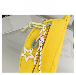 Detail der leuchtend gelben Segeltuchtasche mit bunten Kettenanhängern und Metallreißverschluss