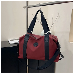 Macro view of burgundy travel bag showing reinforced stitching and durable nylon fabric