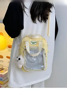 Detalle de bolso Ita de lona amarilla con ventana de PVC transparente y colgante de oso