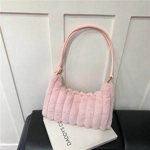 Close-up of pink faux fur shoulder bag with vertical quilted texture on a book