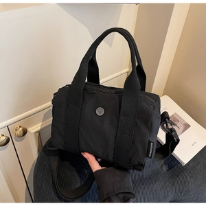 Detailed macro view of black nylon shoulder bag with durable dual handles and woven strap