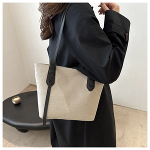 Vue détaillée du sac cabas en toile avoine avec bandoulières en cuir noir et boucle sobre