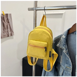 Detail of a bright yellow mini nylon backpack featuring waterproof fabric and zipper pocket