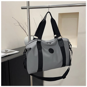 Detail view of a gray travel bag with black straps and detachable shoulder strap on a rack