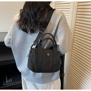 Model wearing a black nylon mini crossbody bag with an adjustable wide strap on the shoulder