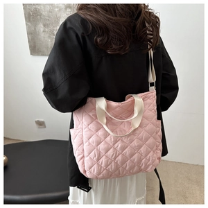 Detail of pink quilted nylon tote bag showing side pockets and fluffy texture on a model