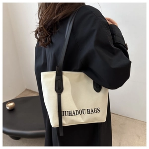 Détail d'un sac cabas en toile minimaliste avec anses en cuir noir et texte imprimé