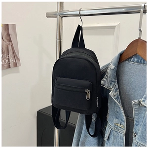 Detail view of the durable black nylon fabric and woven brand label on the mini backpack