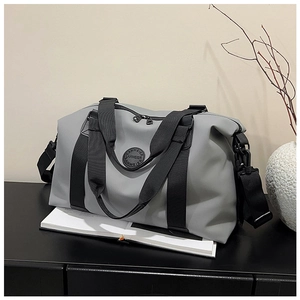 Close-up of gray waterproof travel bag showing texture, black straps and brand logo