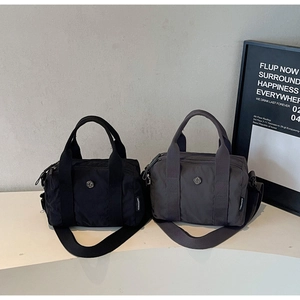 Detail showing two nylon tote bags in black and dark grey with adjustable shoulder straps