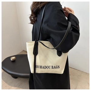 Vue détaillée du sac cabas en toile avec lanières en cuir noir dans un décor minimaliste