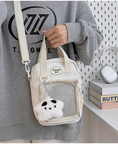 Detalle del bolso bandolera de lona blanca con bolsillo de malla y colgante de estrella