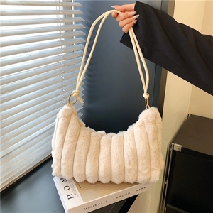 Close-up of fluffy cream faux fur shoulder bag with vertical striped texture and strap