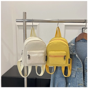 Detail of mini nylon backpacks in beige and yellow with durable adjustable straps