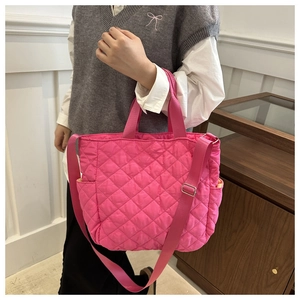 Detailed view of pink quilted nylon tote bag worn by model in a minimalist room