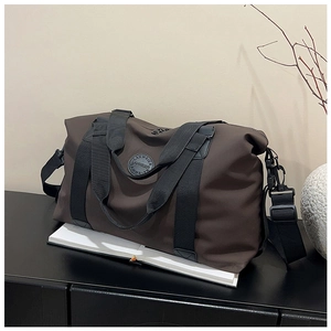 Detailed close-up of dark brown large capacity travel bag with brand logo and strap