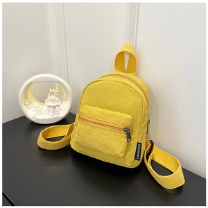 Detail view of mini yellow nylon backpack featuring zipper pockets and side brand label
