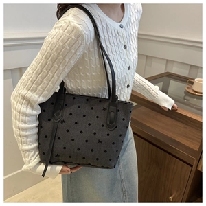 Détail du sac cabas gris à pois avec nœuds porté avec un pull blanc tressé