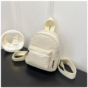 Detail of a beige mini nylon backpack with dual zippers and woven decorative handle