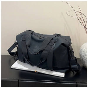Detail view of the black waterproof nylon travel bag with a circular logo on a black table