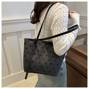 Détail du sac cabas gris à pois avec bandoulière en cuir noir sur l'épaule d'une femme
