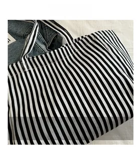 Détails des coutures et des poignées d'un sac cabas en toile à rayures noires et blanches