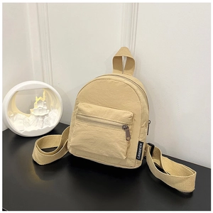 Detail view of water-resistant nylon texture and zipper pocket on beige mini backpack