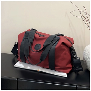 Detail of burgundy travel bag showing durable nylon fabric and round embossed logo