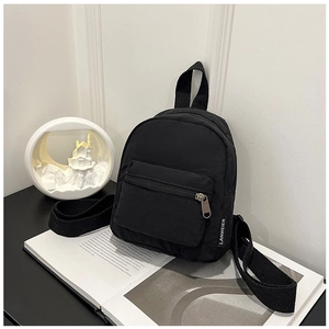 Minimalist black nylon mini backpack featuring a branded tag on a magazine display