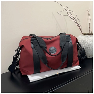 Detail of burgundy travel bag with durable nylon texture and circular logo on black shelf
