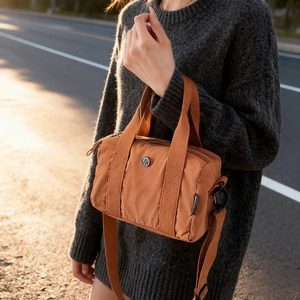 Fashionable orange-brown nylon handbag with adjustable shoulder strap and metal logo
