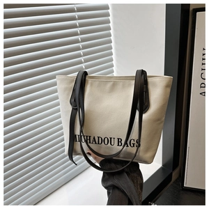 Détail du sac cabas en toile avec bandoulières en cuir noir et logo minimaliste