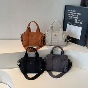 Mini nylon Boston bags in four colors with adjustable straps on a stylish wavy display
