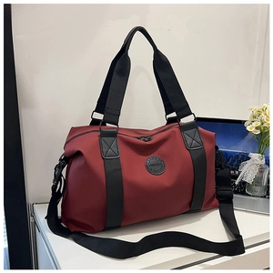 Detail view of burgundy travel bag showing reinforced nylon fabric and leather logo patch