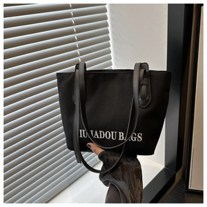 Détail du sac cabas en toile noire avec imprimé IUNADOU BAGS et anses en cuir fin