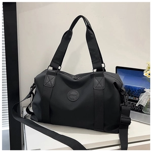 Detail of black travel bag with sturdy handles, logo patch, and adjustable shoulder strap