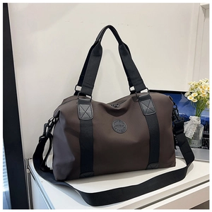 Close-up of brown travel bag with durable black handles and detachable shoulder strap
