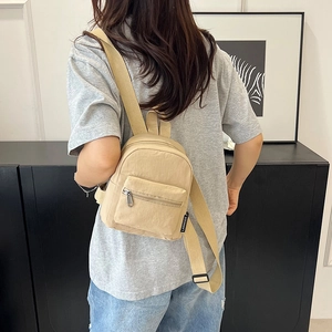 Minimalist khaki nylon mini backpack with textured fabric and front zipper pocket