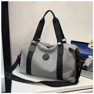 Detailed view of grey travel duffel bag with black straps on a modern office desk