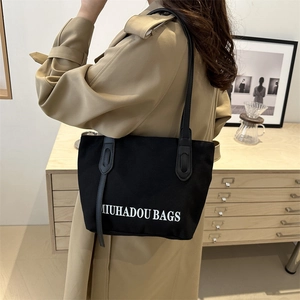 Sac fourre-tout minimaliste en toile noire avec lanières en cuir porté par un modèle