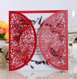 Macro detail of laser-cut red rose pattern invitation with glitter finish and floral inner card