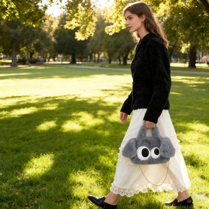Vue détaillée du sac en peluche gris avec yeux de dessin animé et chaîne dorée dehors