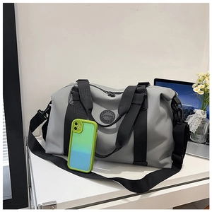 Gray travel bag detail with phone for size comparison on a bright desk setup