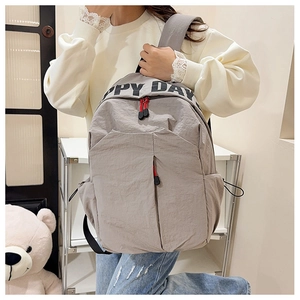 Detail of grey nylon backpack featuring Happy Day print and red zipper puller detail